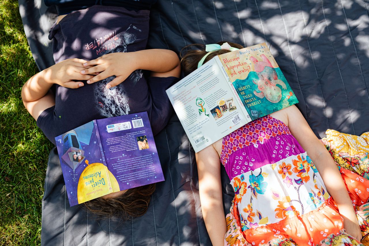 Mastering the First Impression: Your intriguing post title goes here Two children lying on a blanket outdoors with books covering their faces, enjoying a sunny day.